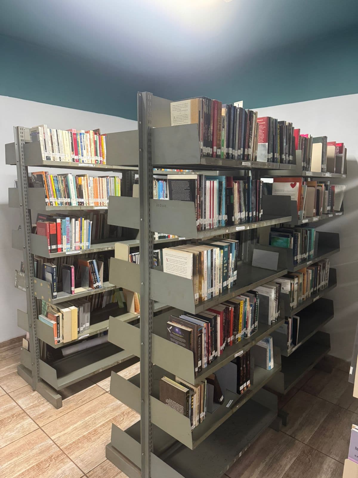 Corredor entre as estantes de livros da biblioteca do CJV